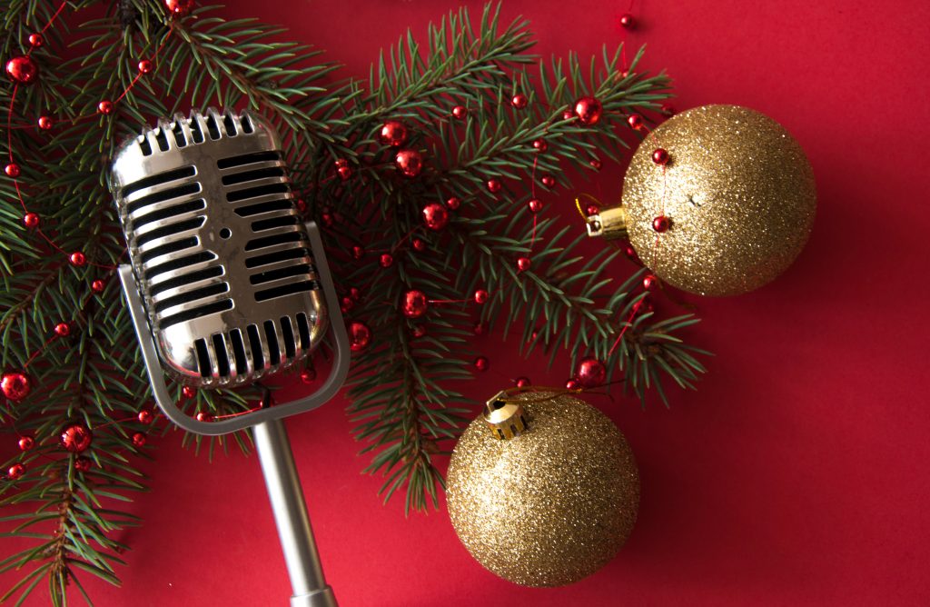Image of microphone on top of pine branches with red beaded garland and gold Christmas ornaments over a red background separating the conclusion from the rest of the article
