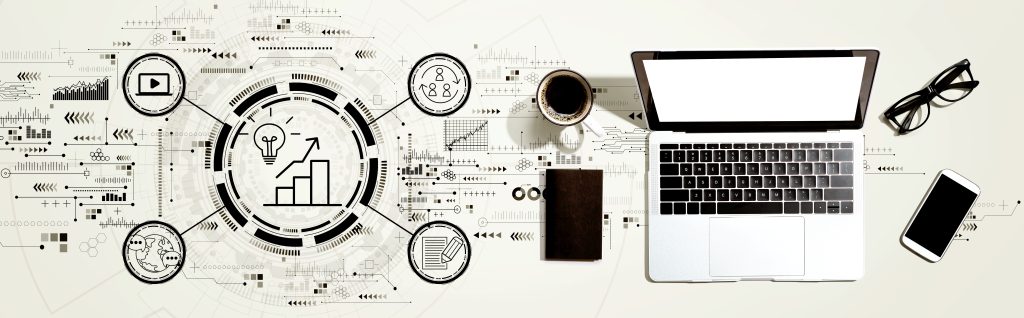 Programmatic Audio Out-of-Home (pAOOH) represents a major leap forward, blending the reach of out-of-home advertising with the impact of dynamic, data-driven audio - Computer and phone, coffee, glasses on desk with graphs and markets symbols